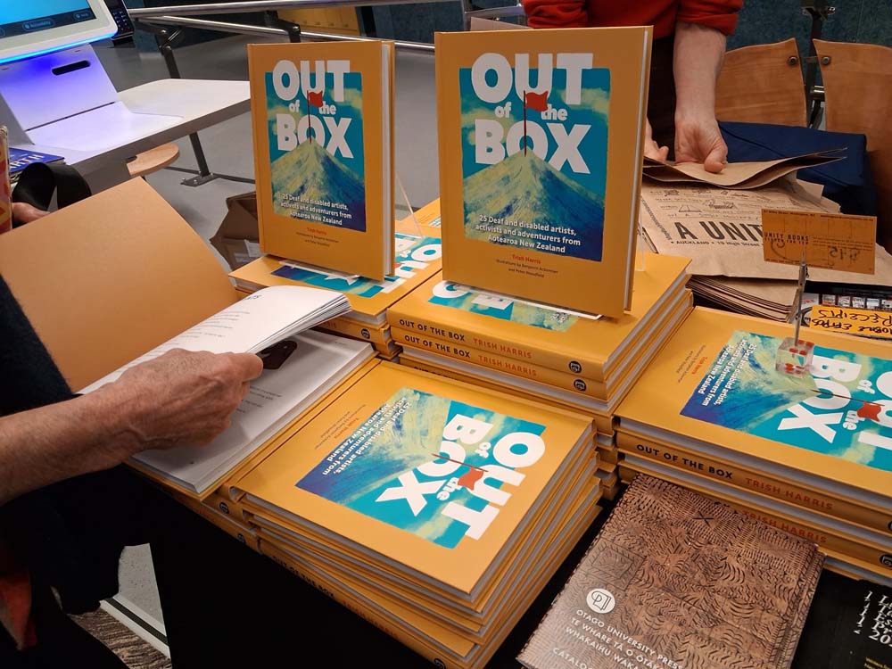 Copies of "Out of the Box" stacked and standing on a sales table at the book launch.